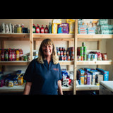 shows employee at the Fylde community hub, in front or stocked shelves 